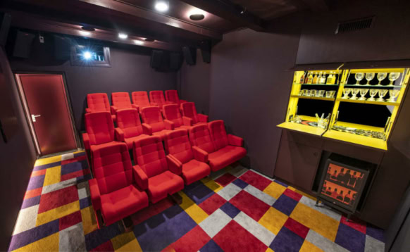 Luxueuze bioscoopzaal met rode fauteuils en kleurrijk tapijt in Cinema Middelburg, perfect voor een comfortabele filmavond in een unieke sfeer.