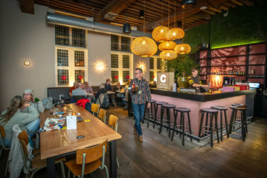 Gezellige bioscoopbar in Cinema Middelburg met comfortabele zitplaatsen voor gasten, warme verlichting en moderne interieur, ideaal voor een ontspannen filmavond met hapjes en drankjes.