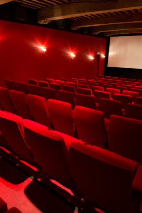 Zwarte cinemazaal met rode stoelen, grote projector en scherm voor een optimale bioscoopervaring in Middelburg.