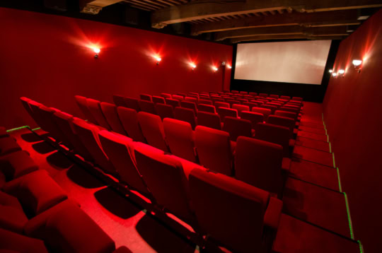 Zwarte cinemazaal met rode stoelen, grote projector en scherm voor een optimale bioscoopervaring in Middelburg.