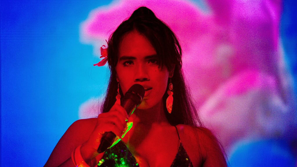 Zangeres met microfoon op podium bij Cinema Middelburg, live muziekoptreden in bioscoop met kleurrijke achtergrond.