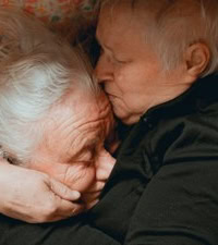 Twee oudere mensen knuffelen warm en liefdevol, een mooie herinnering aan genegenheid in de comfort van huis of zorgomgeving.