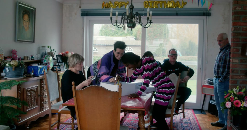Gezinnen vieren verjaardag in een woonkamer met ballonnen en cadeau's, gezellige sfeer, geschikt voor gezins- en familiefilms, interieur van een huis, mensen lachen en genieten.