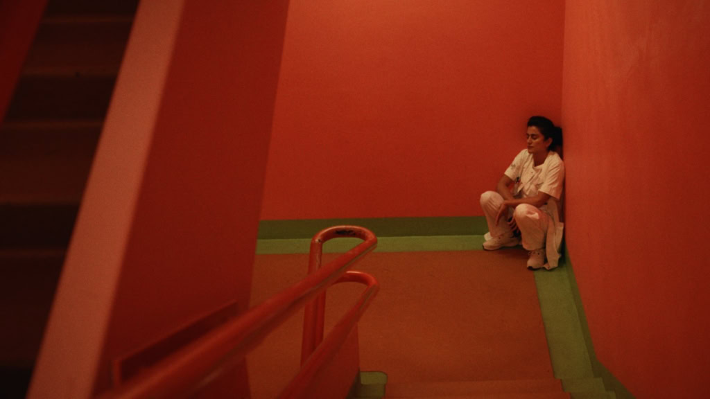 Een vrouw in een witte filmrolstoel kleding zit in een kleurrijke, rustige zaal van Cinema Middelburg, klaar voor een filmvertoning.