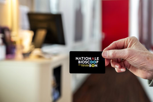 Koper houdt NATIONALE BIOCOOP cadeaukaart in de hand voor toegang tot filmvoorstellingen bij Cinema Middelburg. Relatie tussen bioscoop, kaart, en entertainment in Zeeland.