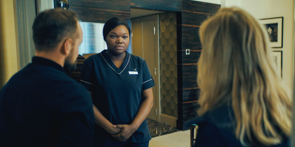 Een scène uit de film Dossier 137 in de bioscoop, met een vrouw die een gesprek voert met twee mensen, mogelijk in een filmvertoning of interview setting, in een gezellige bioscoopomgeving.