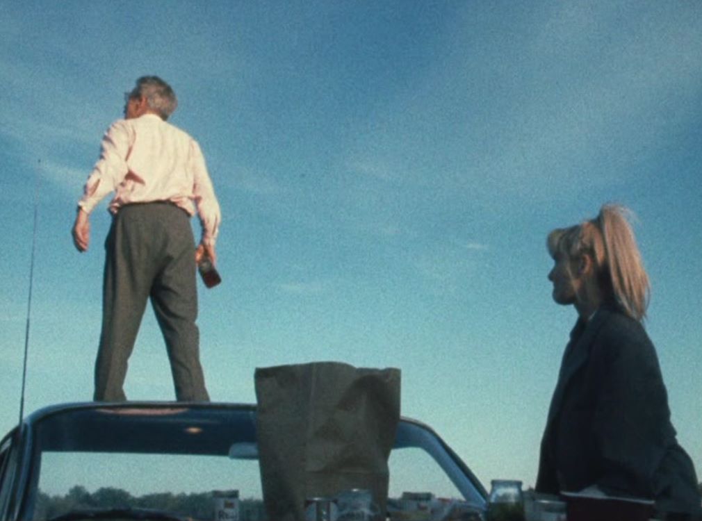 Twee mensen staan op een auto, met een heldere blauwe lucht op de achtergrond, tijdens de vertoning van Wanda (digitale restauratie).
