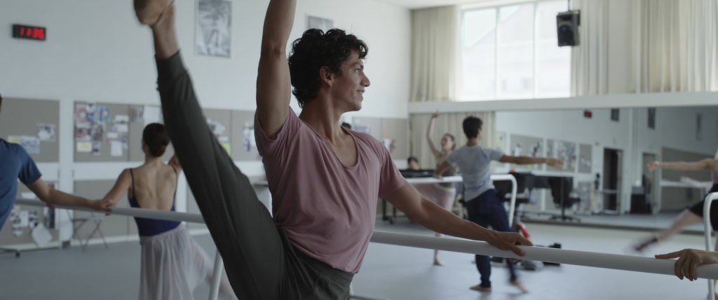 Dansstudio met dansers die oefenen en bewegen, geschikt voor ballet en moderne dans, met grote ramen en spiegels.