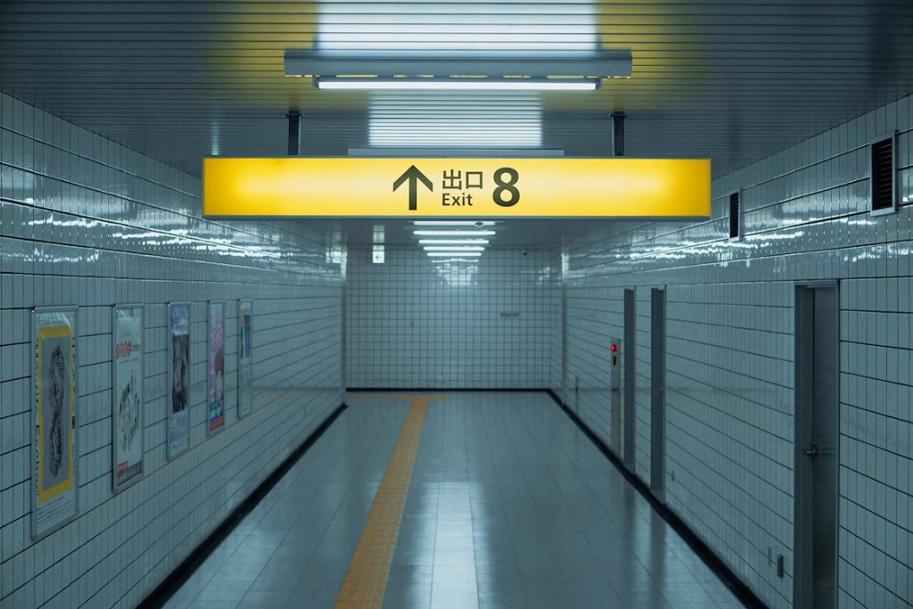 Uitgang 8 in de metro tunnel met duidelijke gele borden en pijl, geschikt voor film- en theaterliefhebbers die de locatie van Exit 8 willen herkennen.