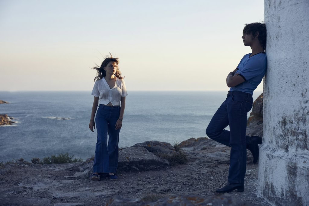 Twee mensen genieten van een rustige wandeling aan de kust, met de zee op de achtergrond. De foto straalt een ontspannen sfeer uit, perfect voor een filmtheater website die sfeer en beleving wil benad.
