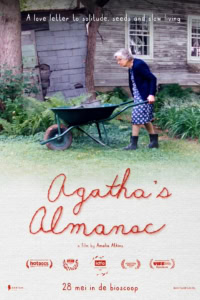 Oudere vrouw met grijs haar die een tuinwielwagen duwt voor een oude houten schuur, symboliseert rust en reflectie, passend bij de film 'Agatha's Almanac' over stilte en langzamer leven.
