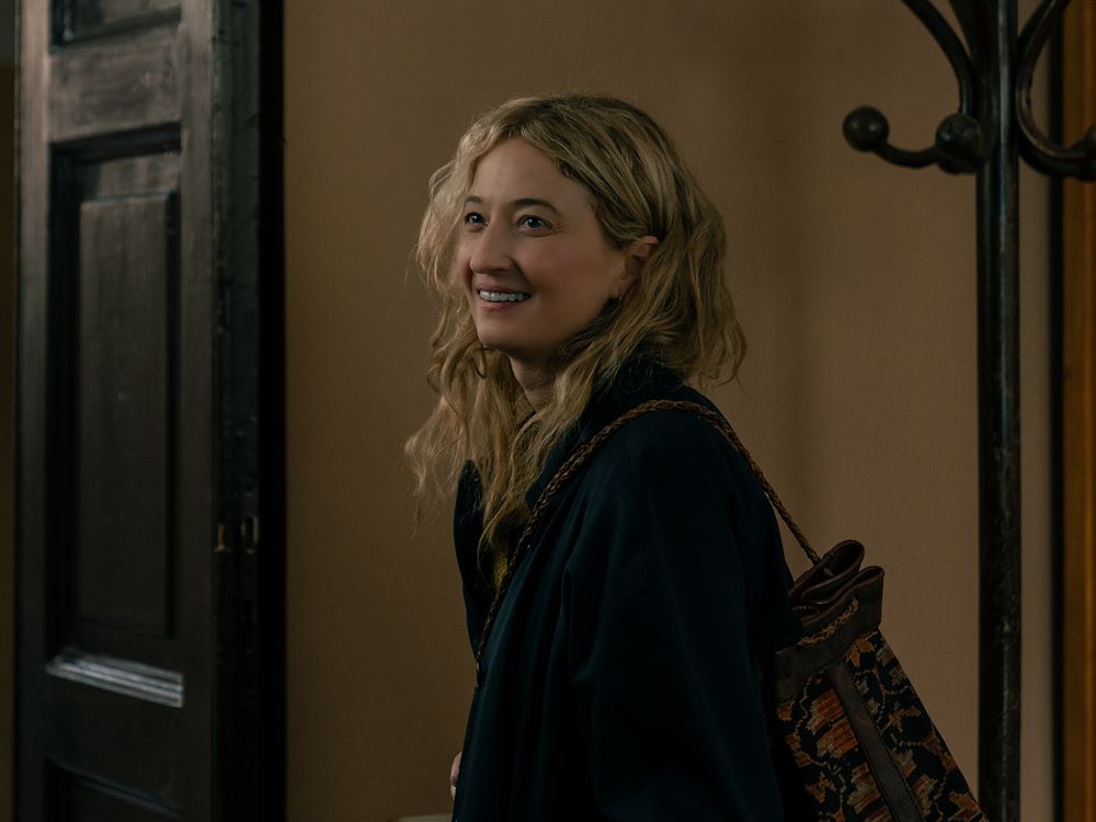 Vrouw met glimlach bij de ingang van de bioscoop, promotie voor de film "Tre Ciotole" met een warme sfeer en uitnodigende uitstraling.