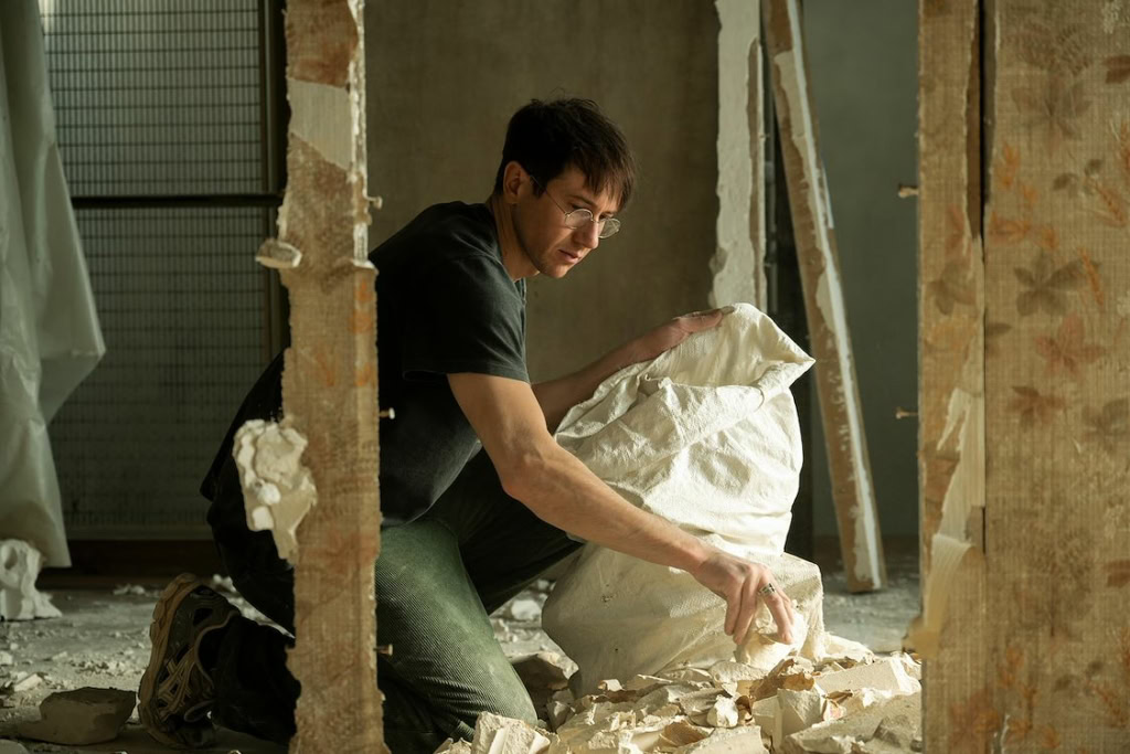 Man die een muur afbreekt met sloopgereedschap in een bouw- of renovatieproject, binnen een bouwplaats met ruwe muren en bouwmaterialen, geschikt voor een filmtheater website.
