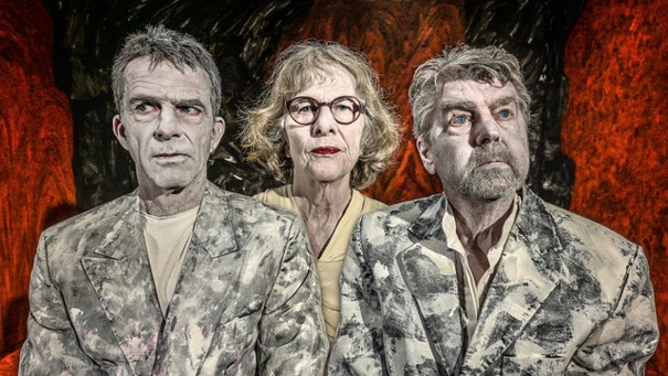 Drie acteurs in vintage kostuums op een filmset met een dramatische achtergrond, passend bij een klassiek filmtheater in Middelburg.
