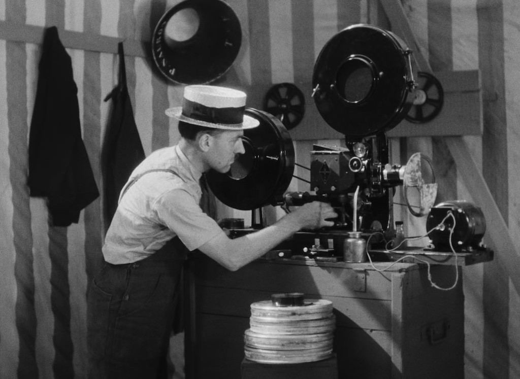 Jonge man bedient een oude filmprojector in een filmstudio, zwart-wit foto, vintage sfeer, filmproductie, filmtechniek, filmprojectie, filmstudio, filmindustrie, filmkunst, filmgeschiedenis, filmtechn.