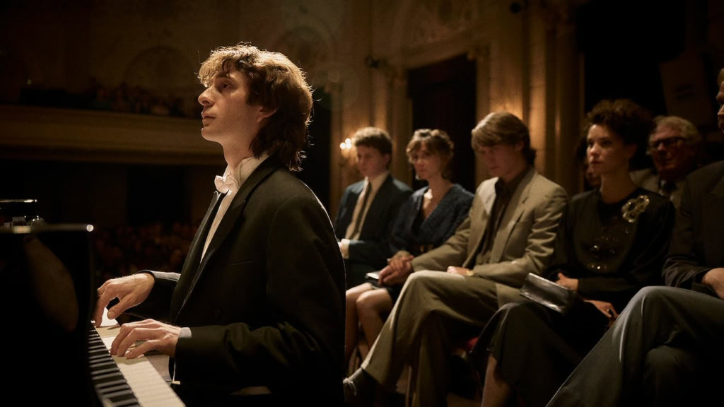 Mooie concertpianist speelt op een groot podium met een publiek in een elegante zaal, onder warme verlichting, tijdens een live uitvoering.