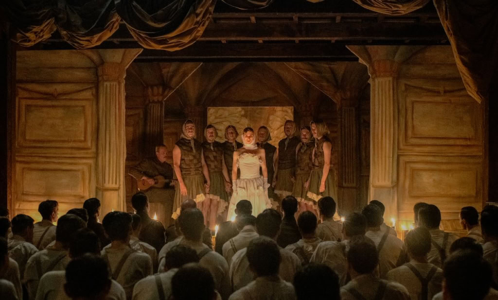 Toneelvoorstelling met acteurs op een podium voor een publiek in Cinema Middelburg, sfeervol verlicht met houten decor en gordijnen.