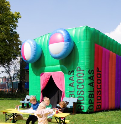 Kinderen genieten van een opblaasbare bioscoop voor kinderen tijdens een evenement in de buitenlucht.
